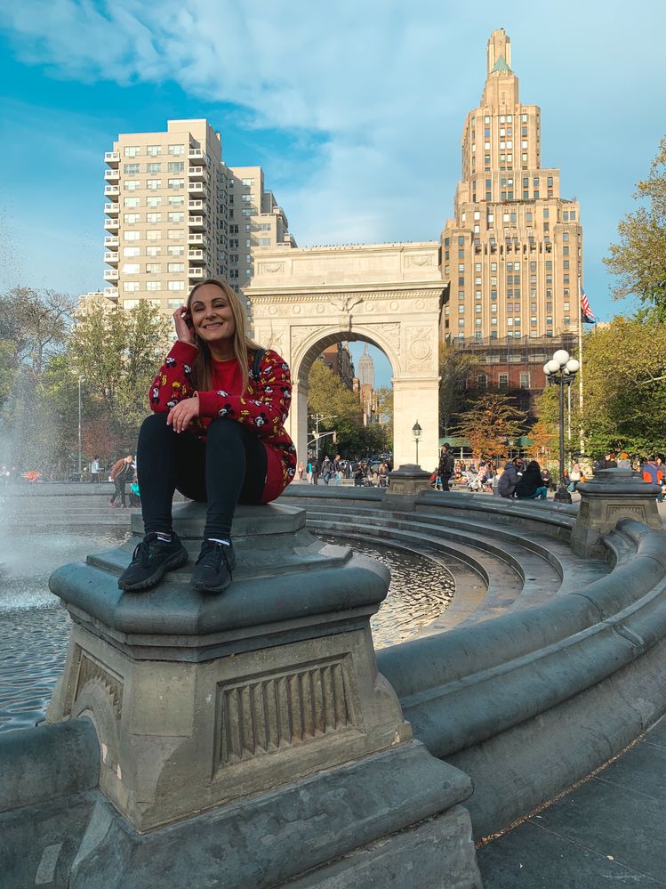 Caption: A photo of Penny sitting next to a fountain in front of the Washington Square Arch in New York City. (Courtesy of Local Guide @PennyChristie)