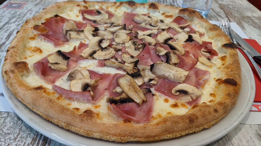 Caption: A photo of a white pizza with ham, mushrooms, and cheese from Pizzeria Chez Ciccio in Vevey, Switzerland. (Local Guide @christophesubilia)