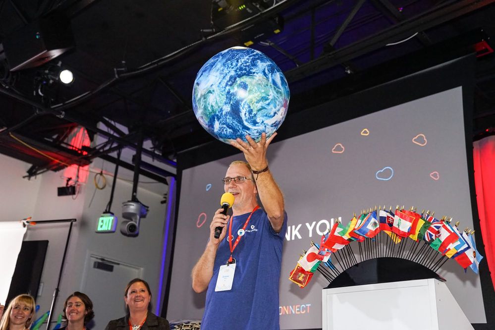 Caption: A photo of Local Guide Ermes Tuon holding a model of the Earth and giving a speech during Connect Live 2018.