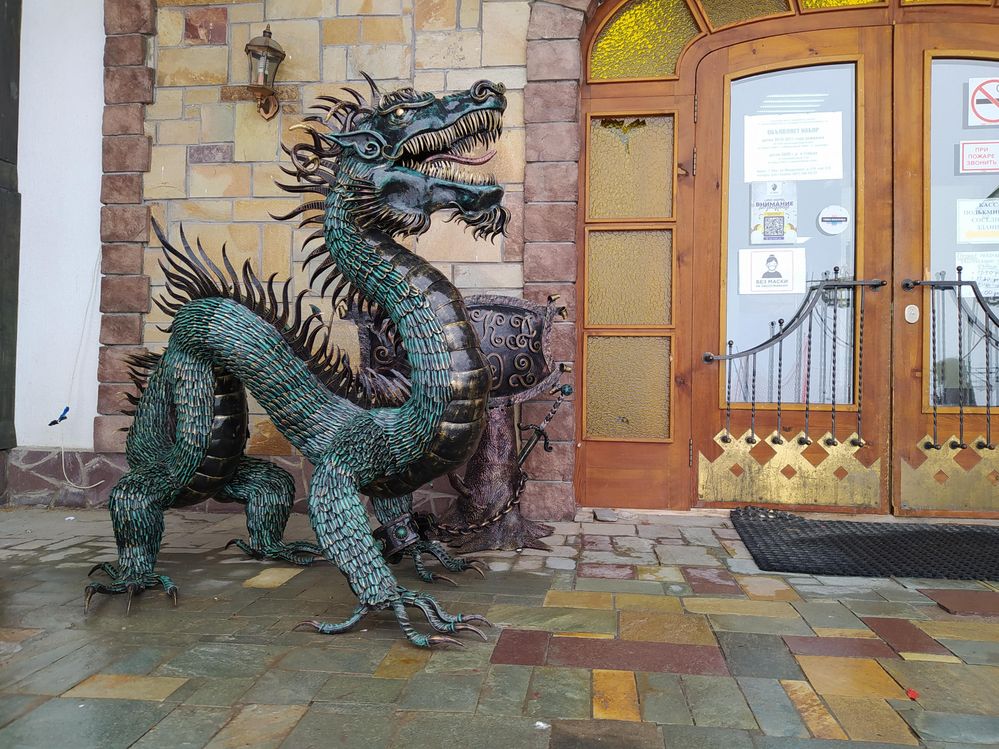 Caption: A bluish-green Dragon with brass underbelly sculptor standing entrance door to one of the hotel’s buildings.