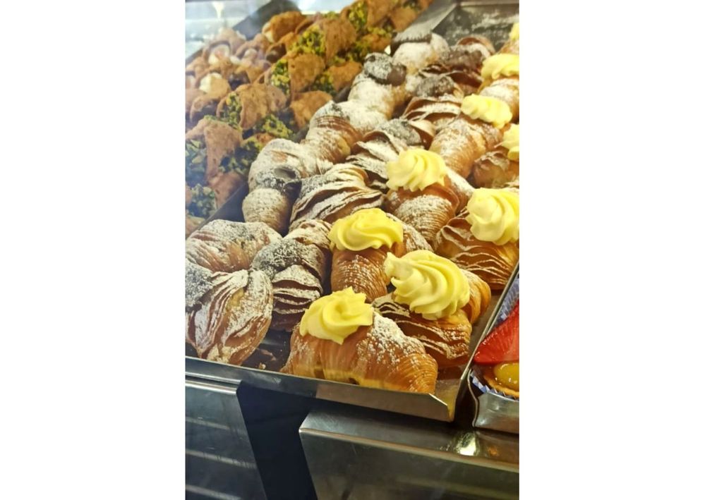 Caption: A photo of aragostine topped with cream and powdered sugar on display in a shop window. (Local Guide @BorrisS)