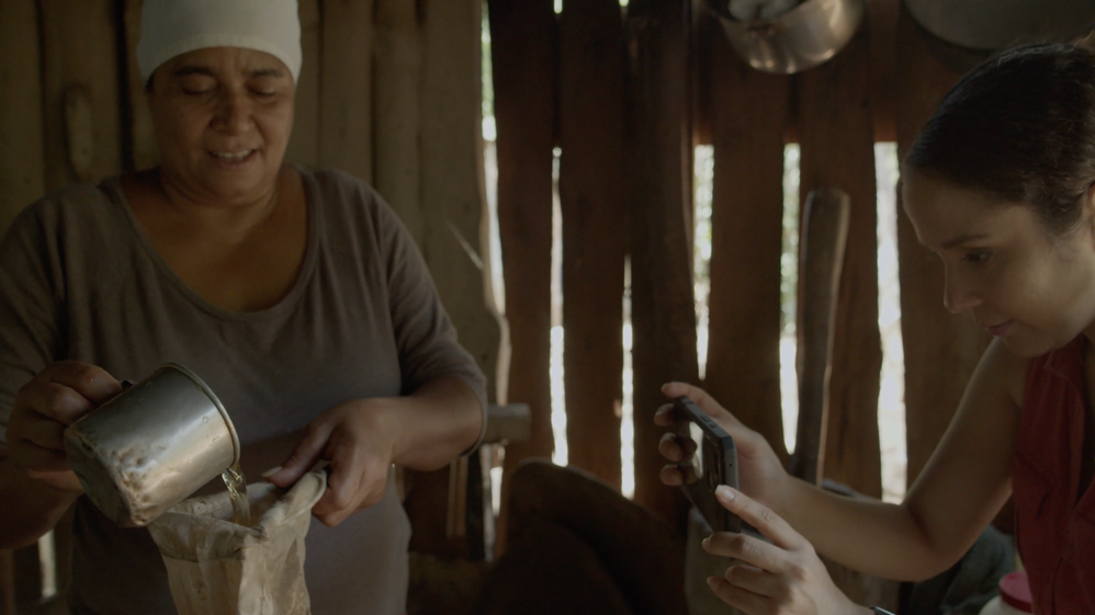 Caption: A photo of Maricha taking a video of a woman making traditional coffee.