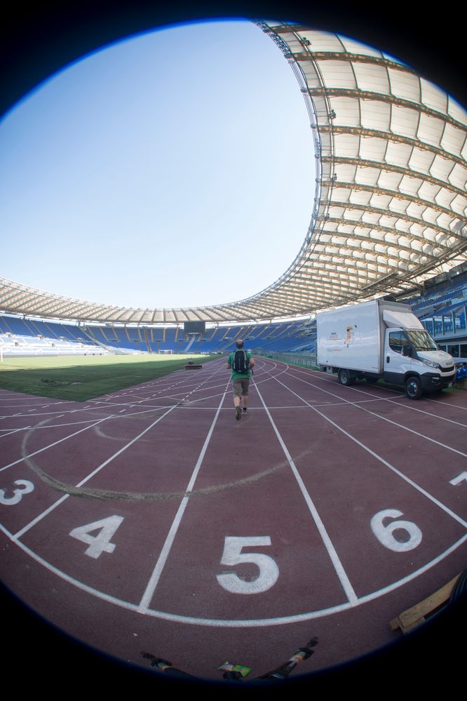 A local guide running in an empty stadium while doing 360 photography