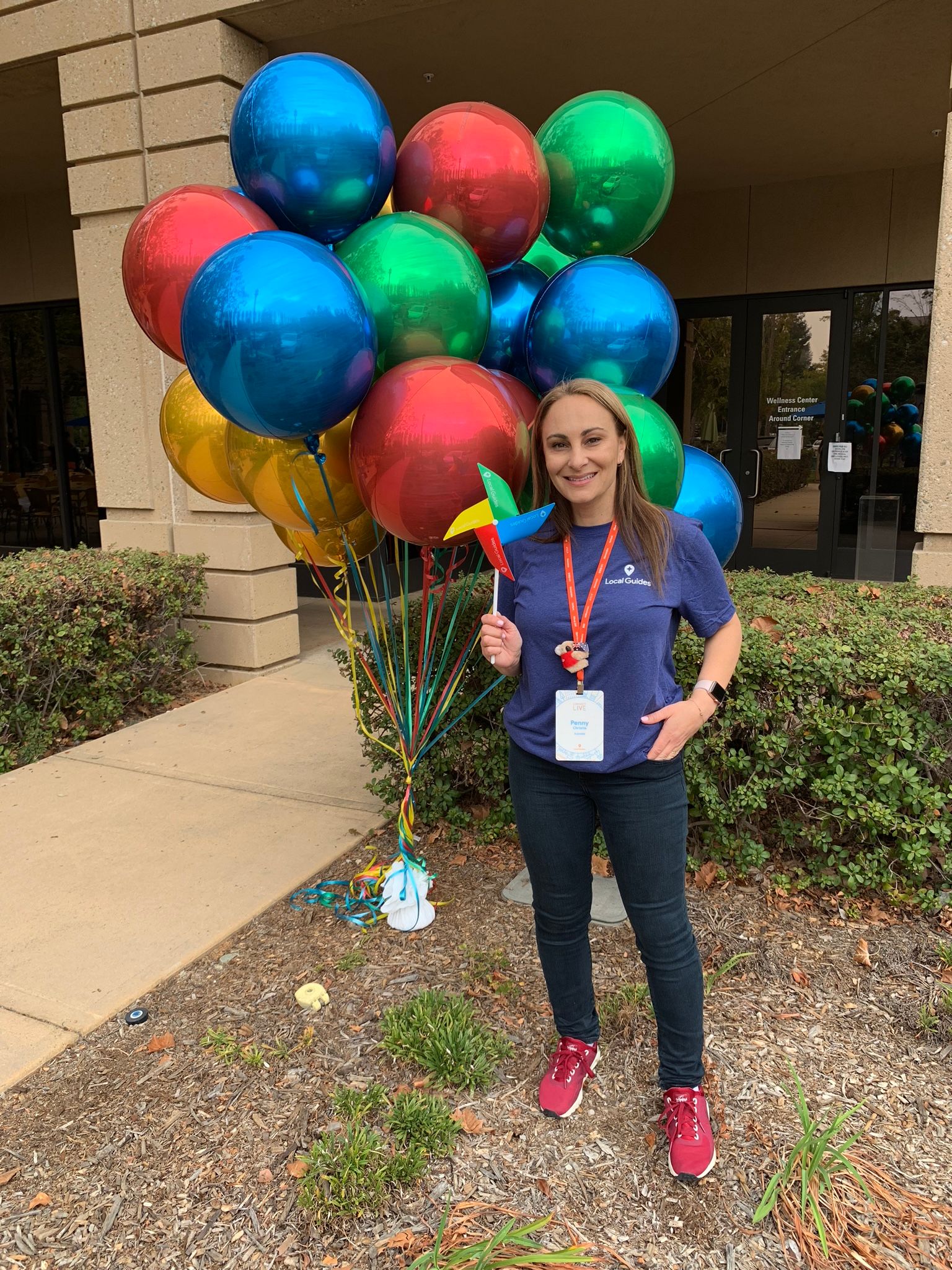 Caption: A photo of Penny Christie posing in front of blue, red, green, and yellow balloons at  Google headquarters during Connect Live 2018. (Local Guide @PennyChristie)