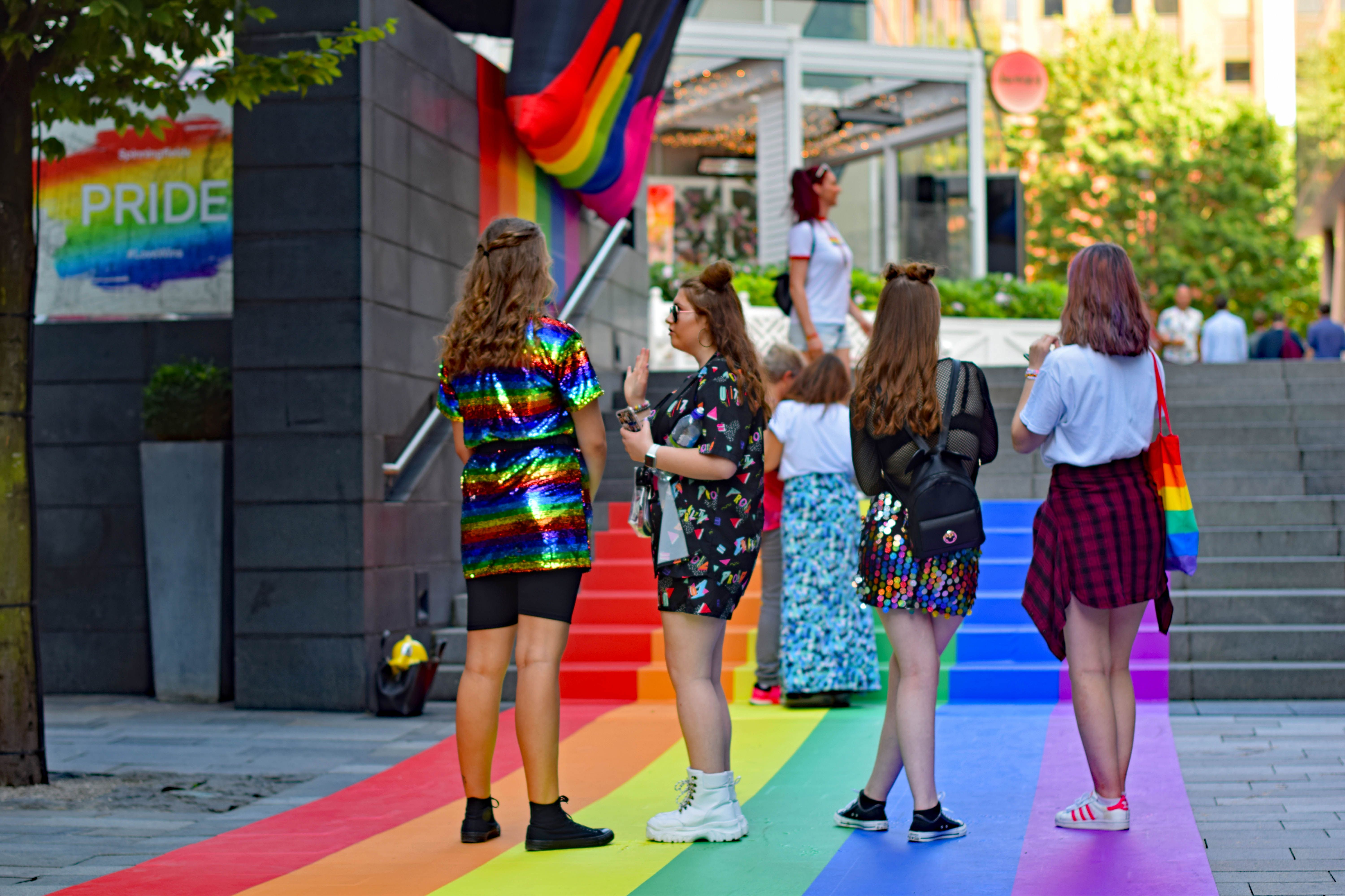 Artwork in the Spinningfields financial center  of the city with young women standing on a rainbow pained pavement