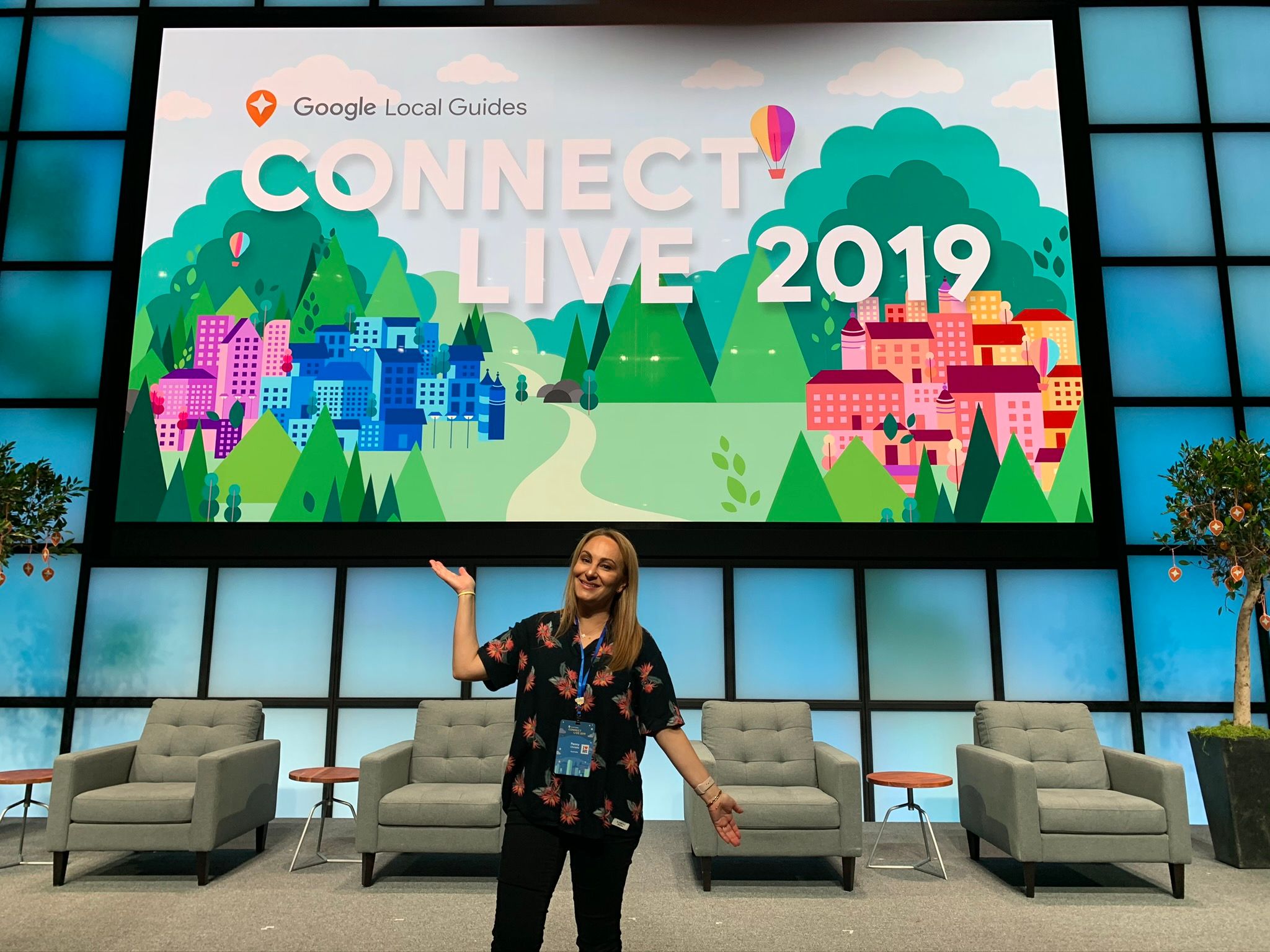 Caption: A photo of Penny posing in front of a big screen with the text “Google Local Guides, Connect Live 2019” on it. (Courtesy of Local Guide @PennyChristie)