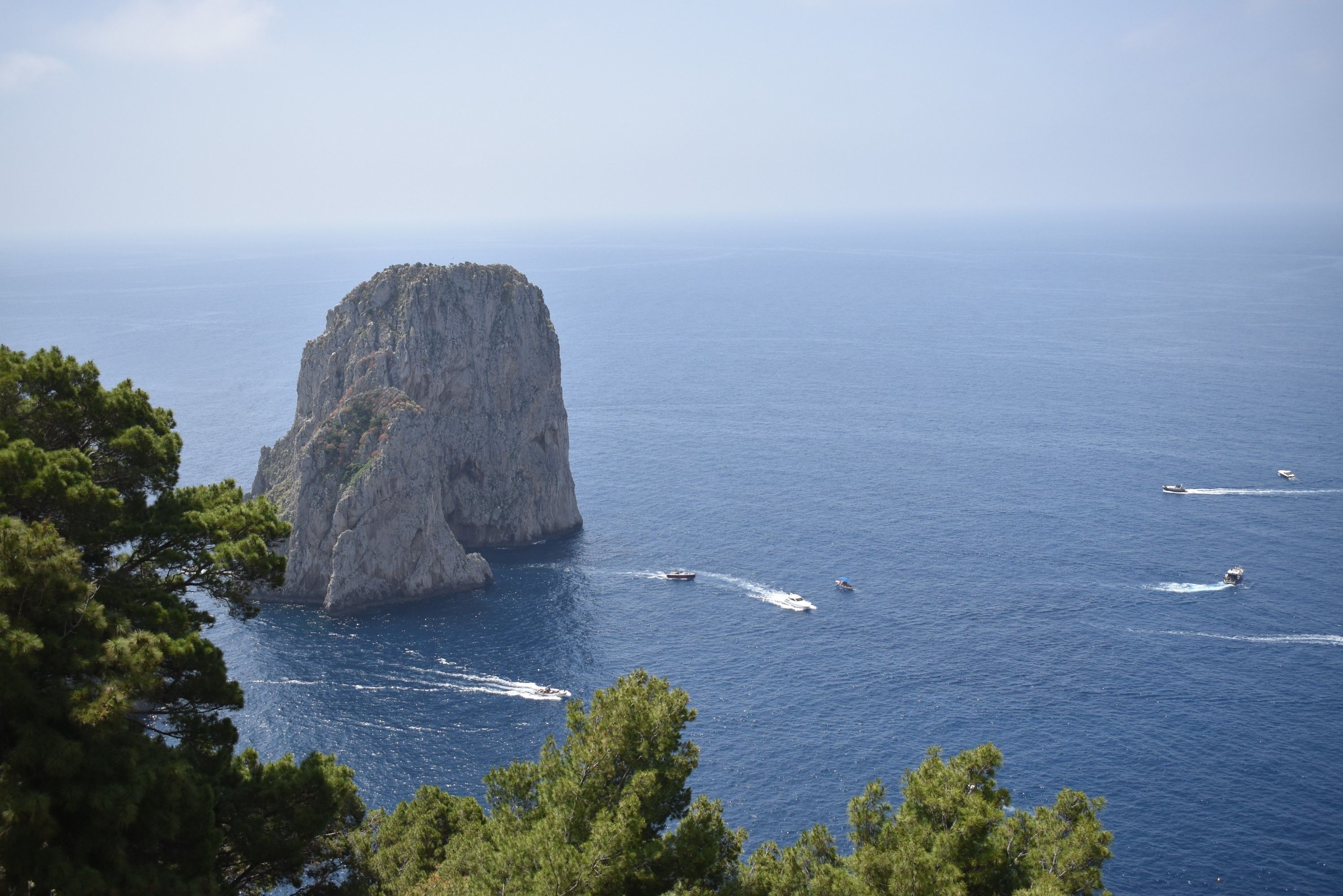 Caption: A photo of a towering rock formation in the sea and several boats roaming around it. (Local Guide @MoniDi)
