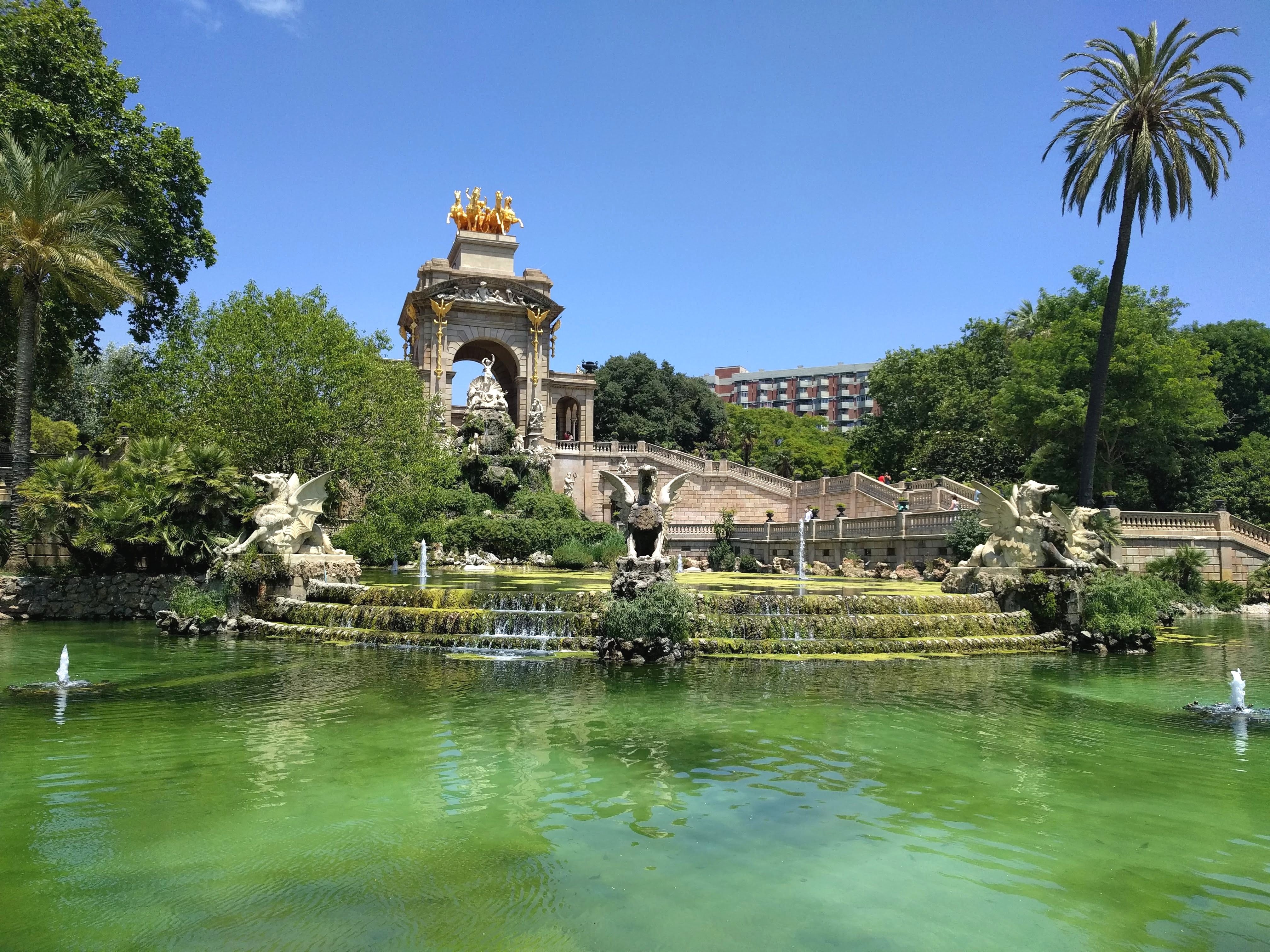Caption: A photo of the Cascada Monumental Fountain and greenish lake in front of it, with several lush green trees around it. (Local Guide @MoniDi)