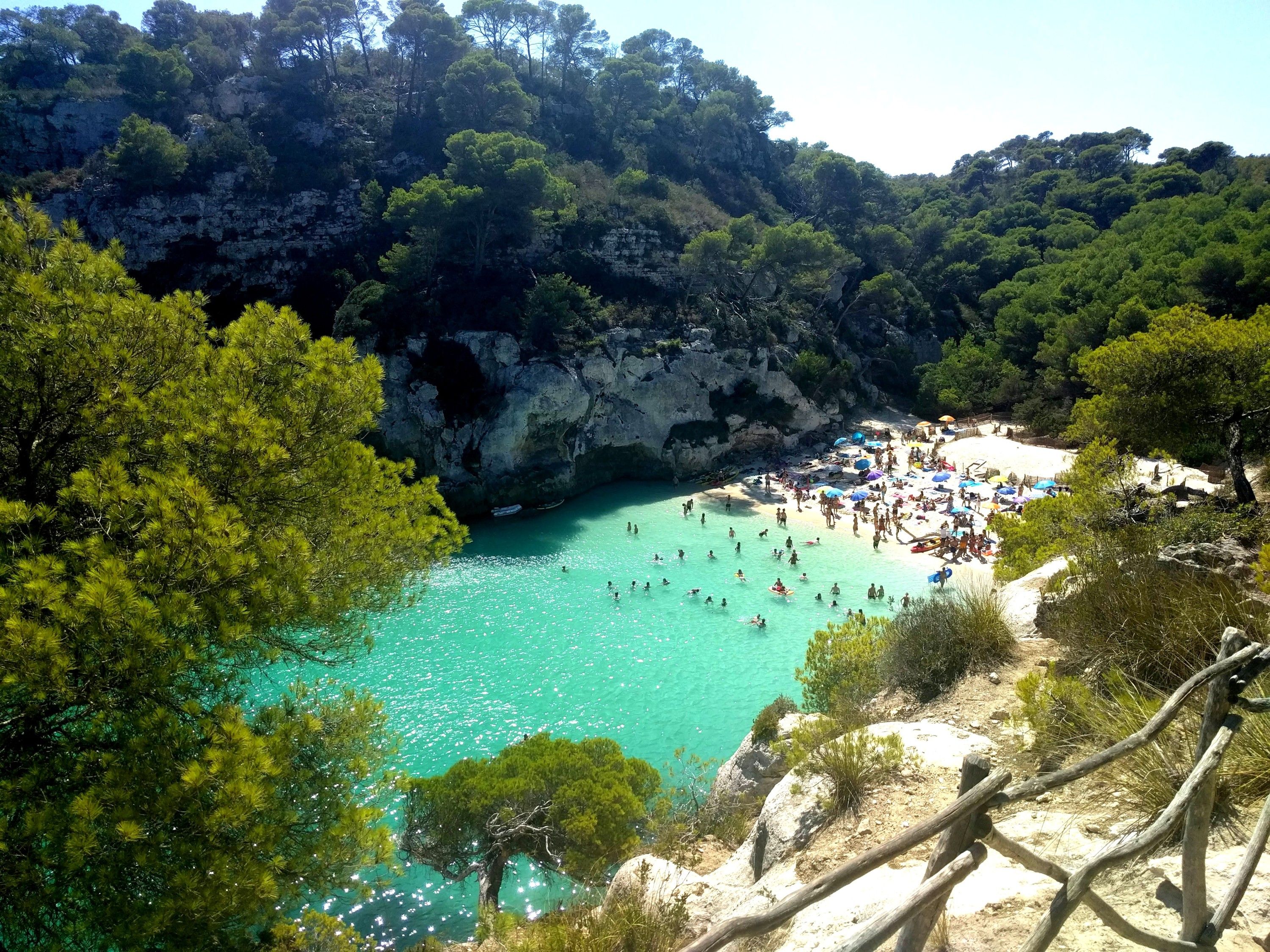 Caption: A photo of the secluded Macarelleta Beach from a high point, showing people sunbathing and swimming in the water. (Local Guide @MoniDi)