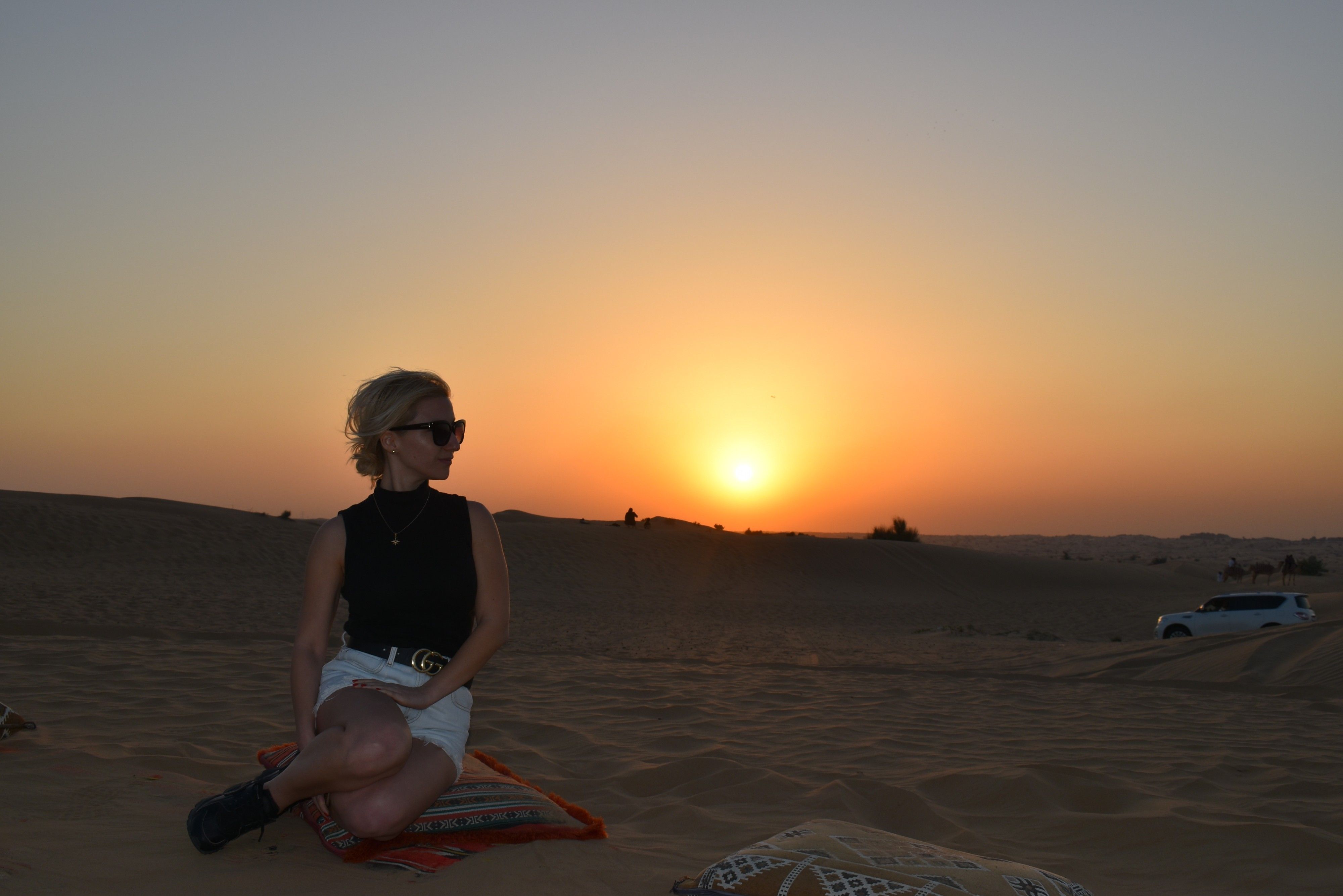 Caption: A photo of Google Moderator @MoniDi sitting on a cushion in the Arabian Desert in Dubai at sunset. (Local Guide @MoniDi)