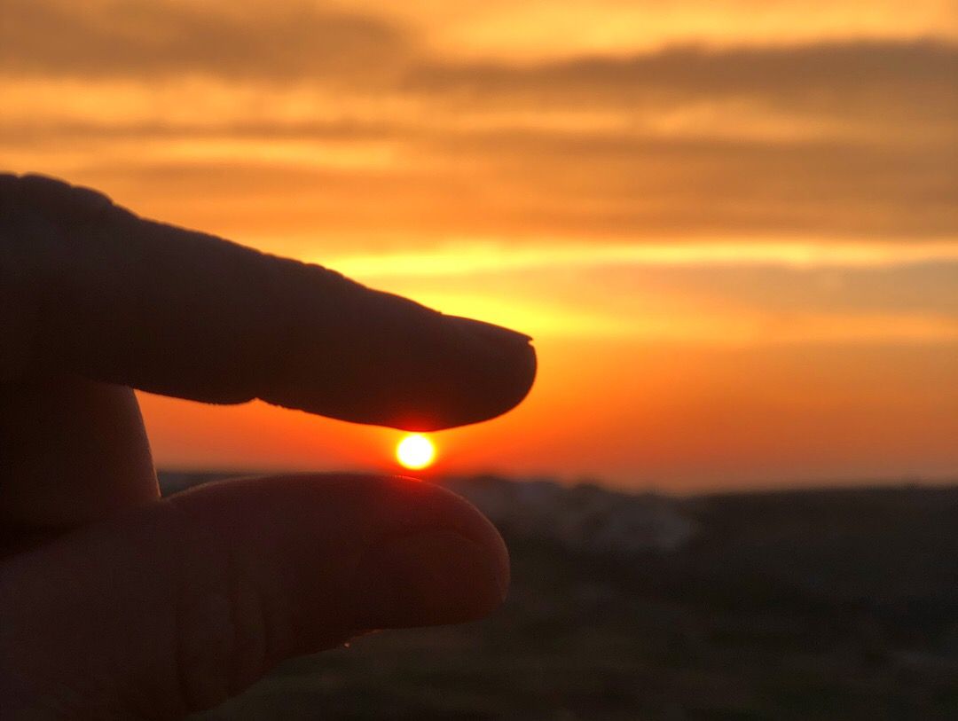Caption: A photo of the setting sun framed between two fingers in Malta. (Local Guide @AlexTravel)