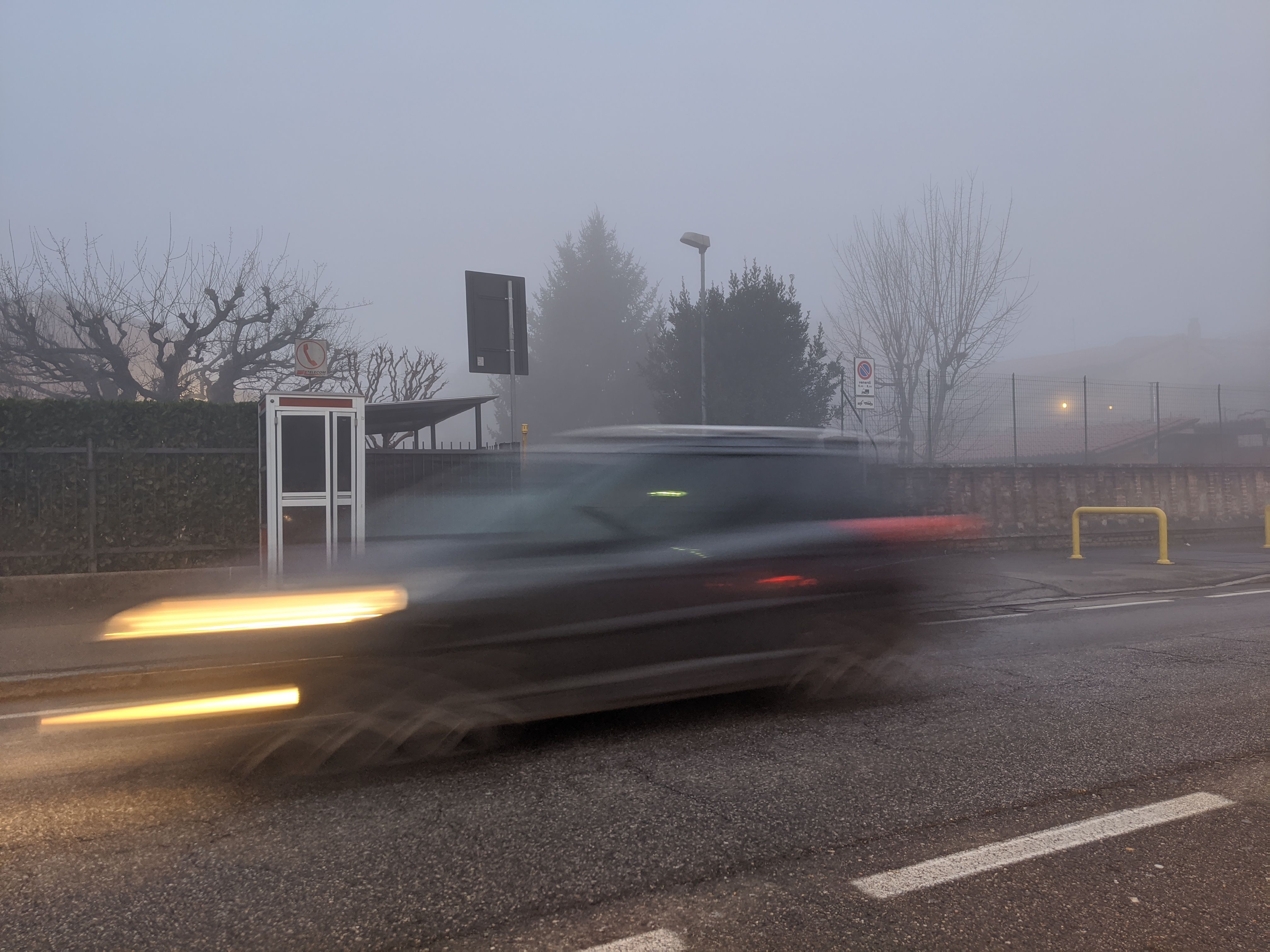 Picture of a car passing a street with fog