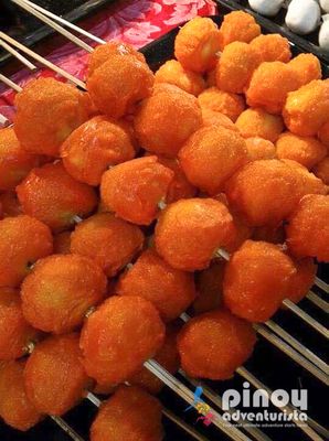 This is called "kwek-kwek", a hard boiled egg of chicken or quails covered with orange batter then fried. It's best eaten dipped in vinegar.