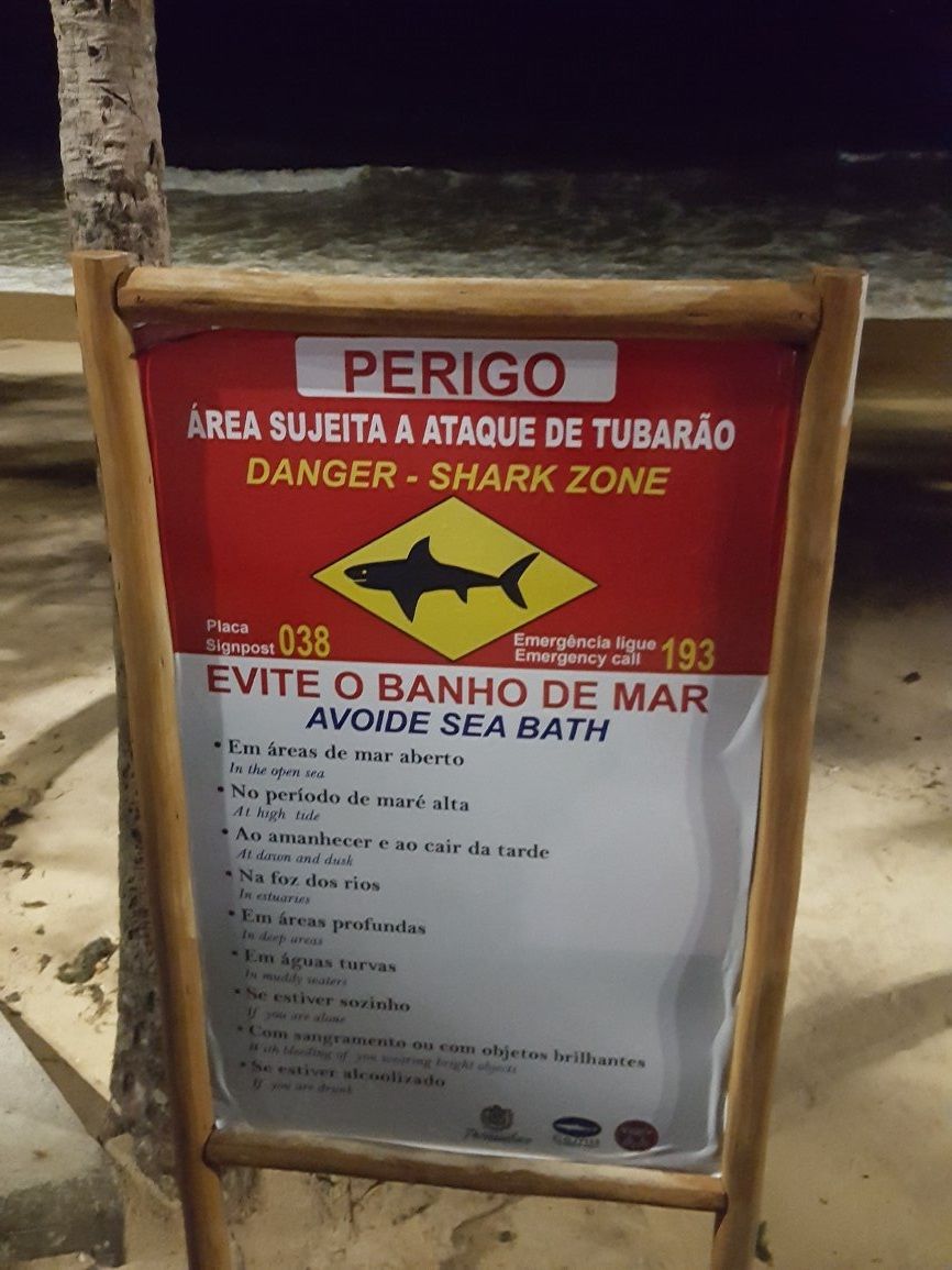 Placa alertando sobre o risco de tubarões