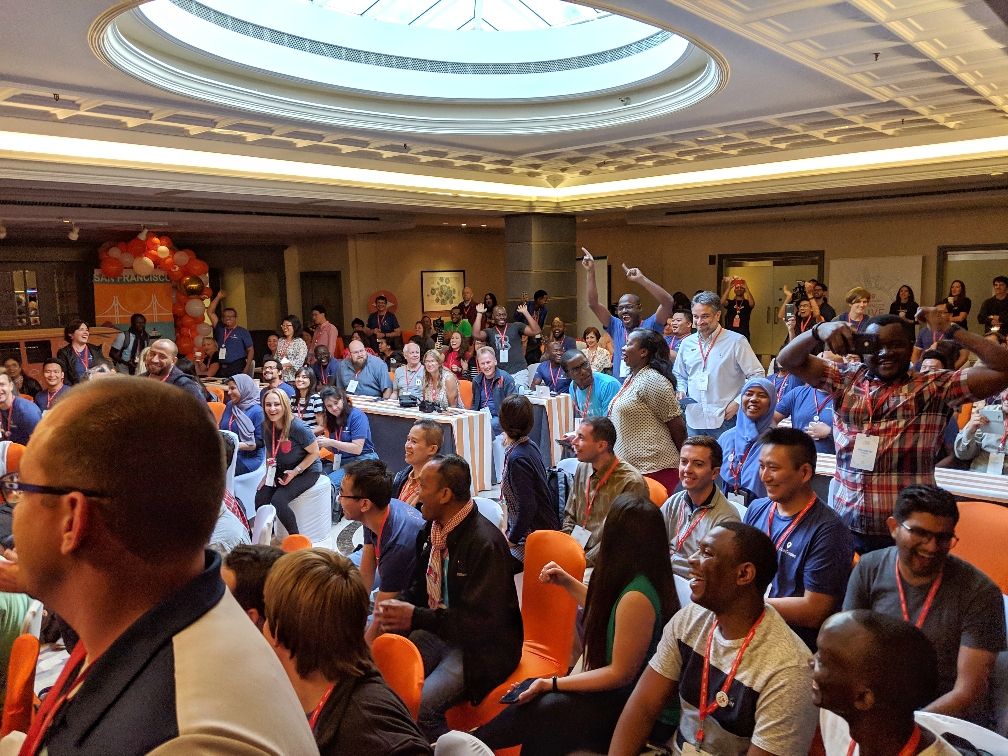Caption: A photo of Local Guide attendees sitting in the audience and cheering at Connect Live 2018.