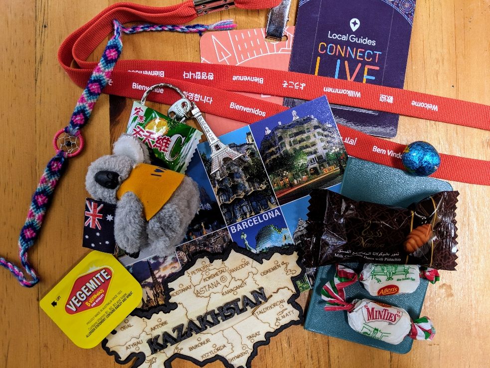 Caption: A photo of gifts I received throughout Connect Live 2018 including a small stuffed koala, candies, an Eiffel Tower key chain, a postcard, and more.
