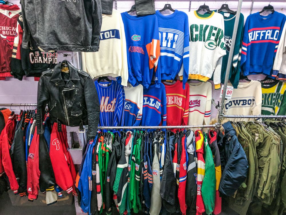 Caption: A photo of vintage sports attire for sale on shelving in a vintage clothing store. (Wendy George)
