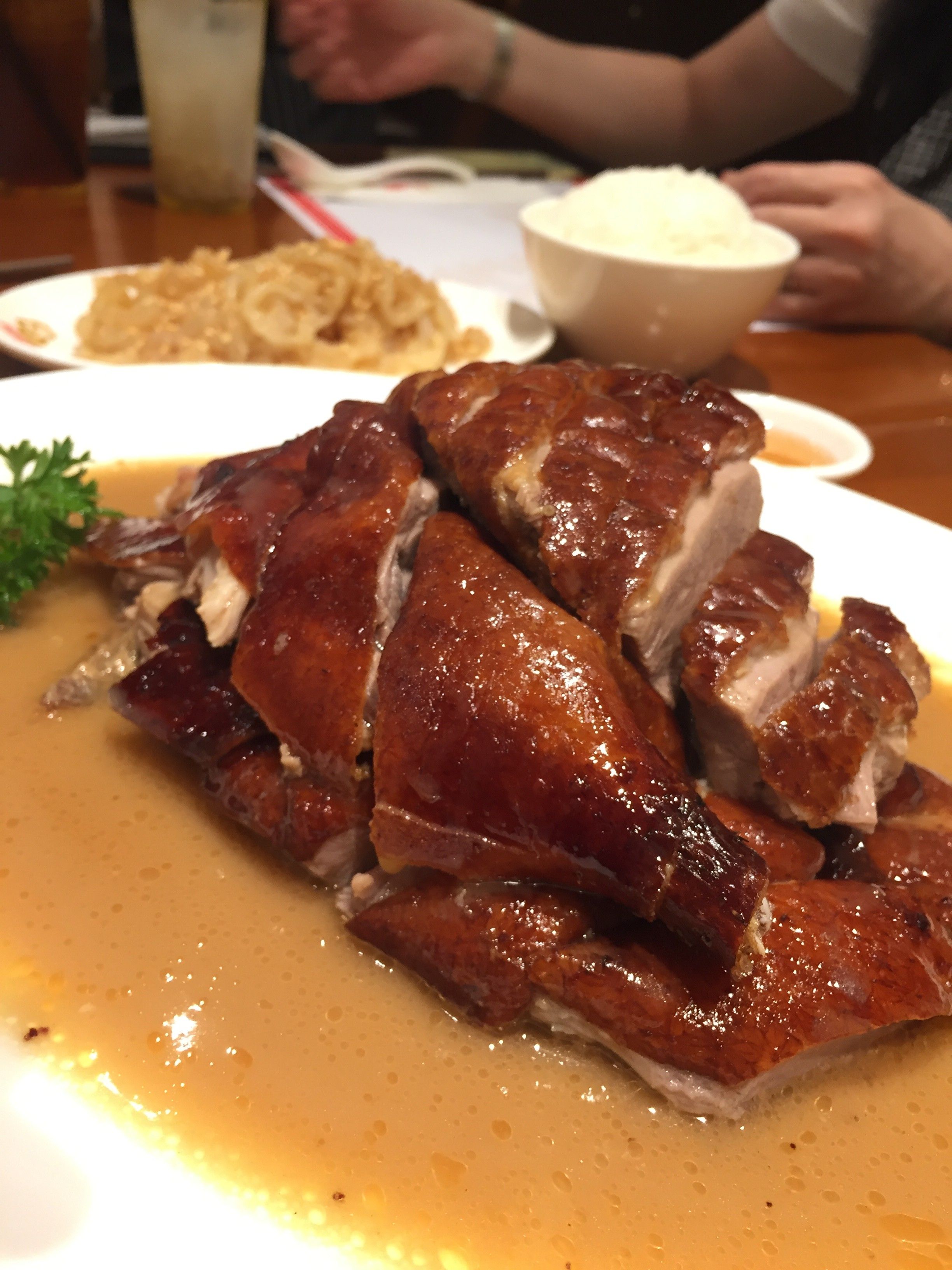 Caption: A photo of the roasted duck specialty at Kam’s Roast in Singapore. The meat is cut in big chunks, but still held together, with brownish sauce underneath.  (Local Guide @AngieYC)