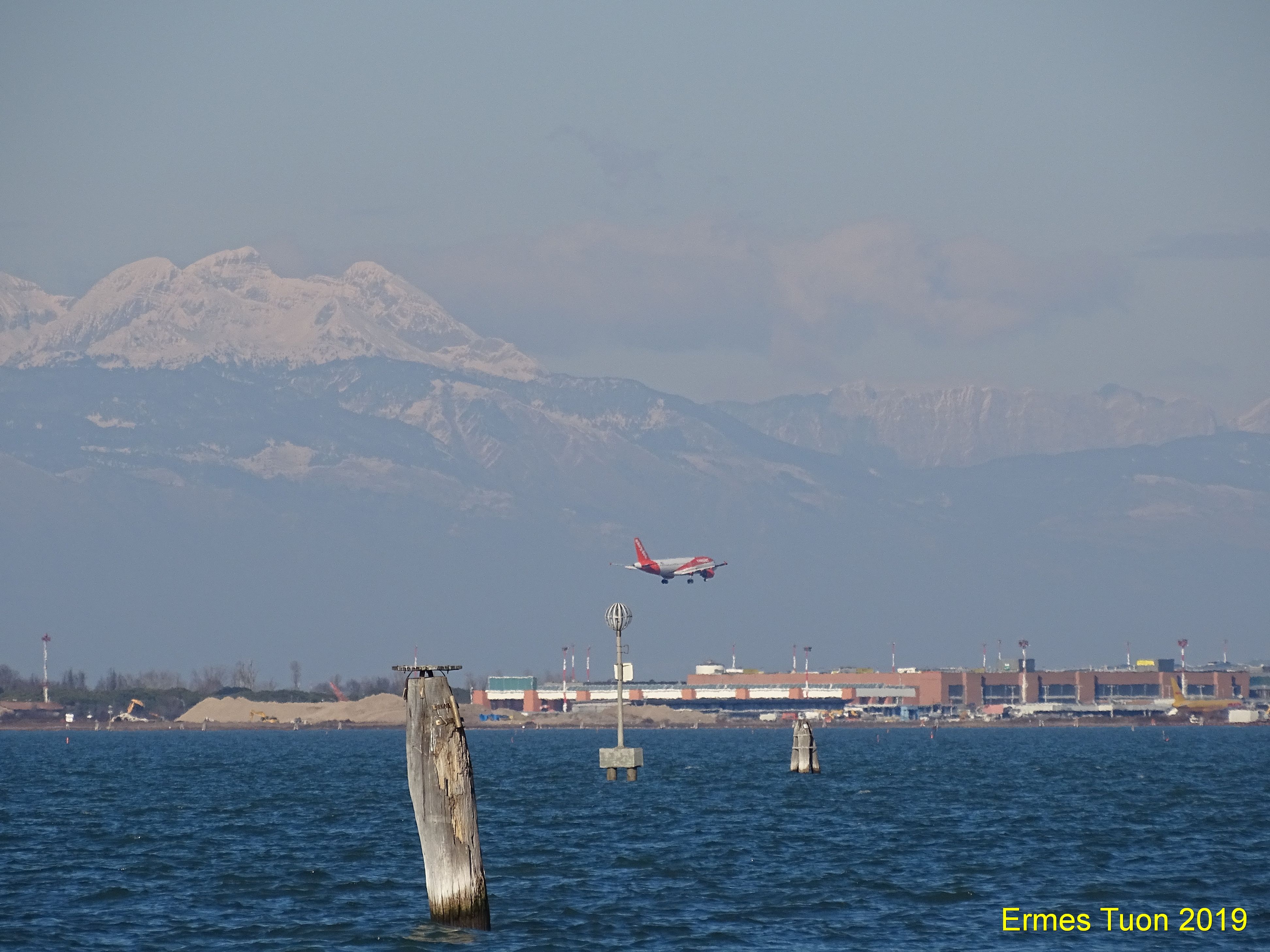 Caption: A flight is landing to VCE Airport, in a view from Venice - in the background you can see the Dolomites Mountain - Local Guide @ermest