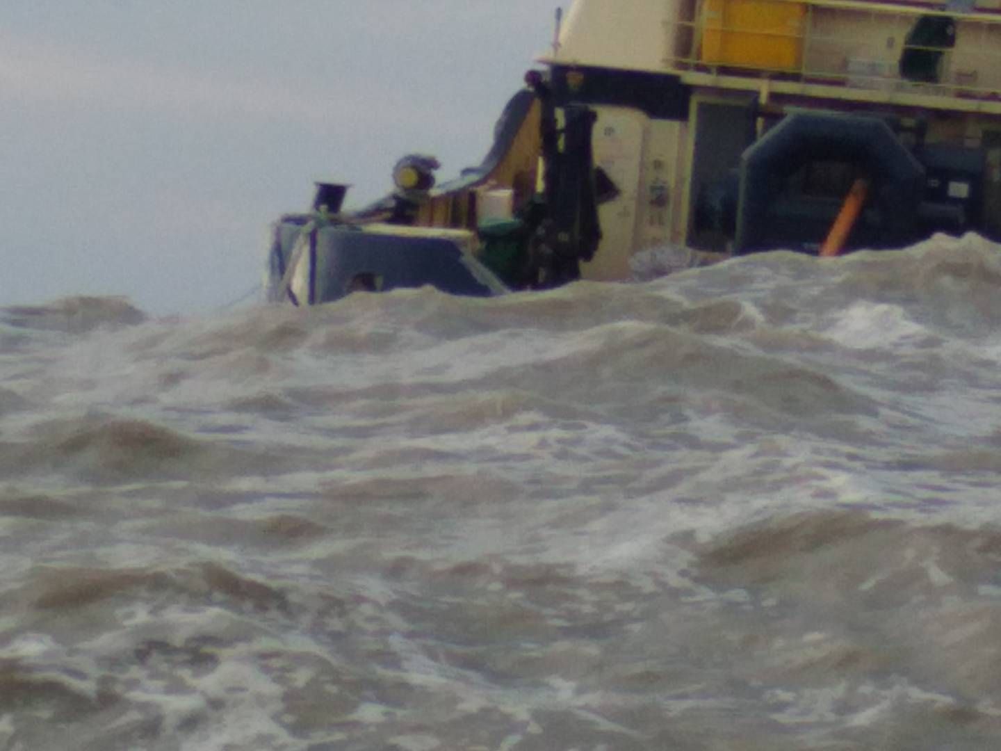 Working on a tug boat at sea during rough sea. Photo taken from a small boat during salvage work at sea..