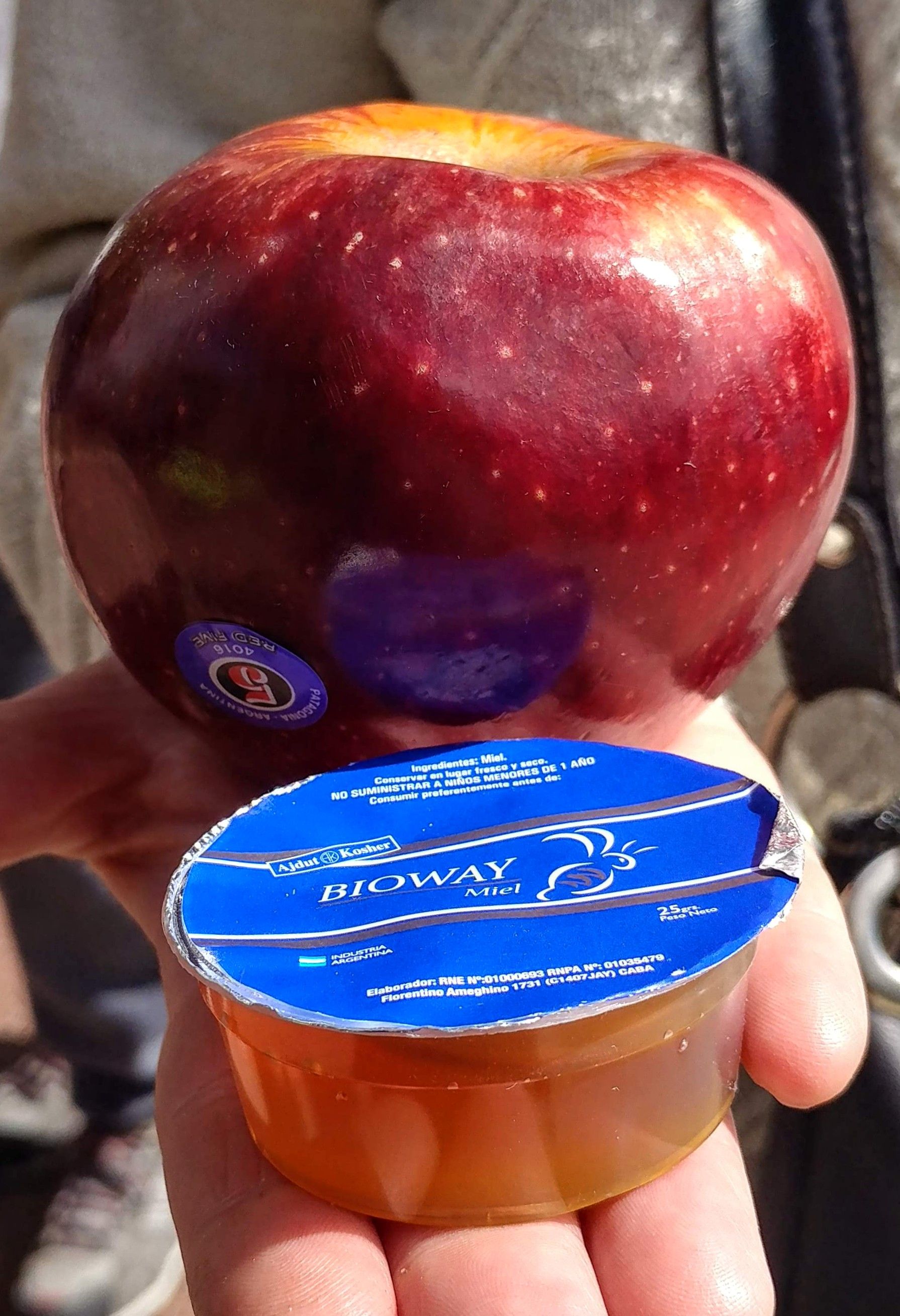 Caption: A red apple and a sealed packet of honey.