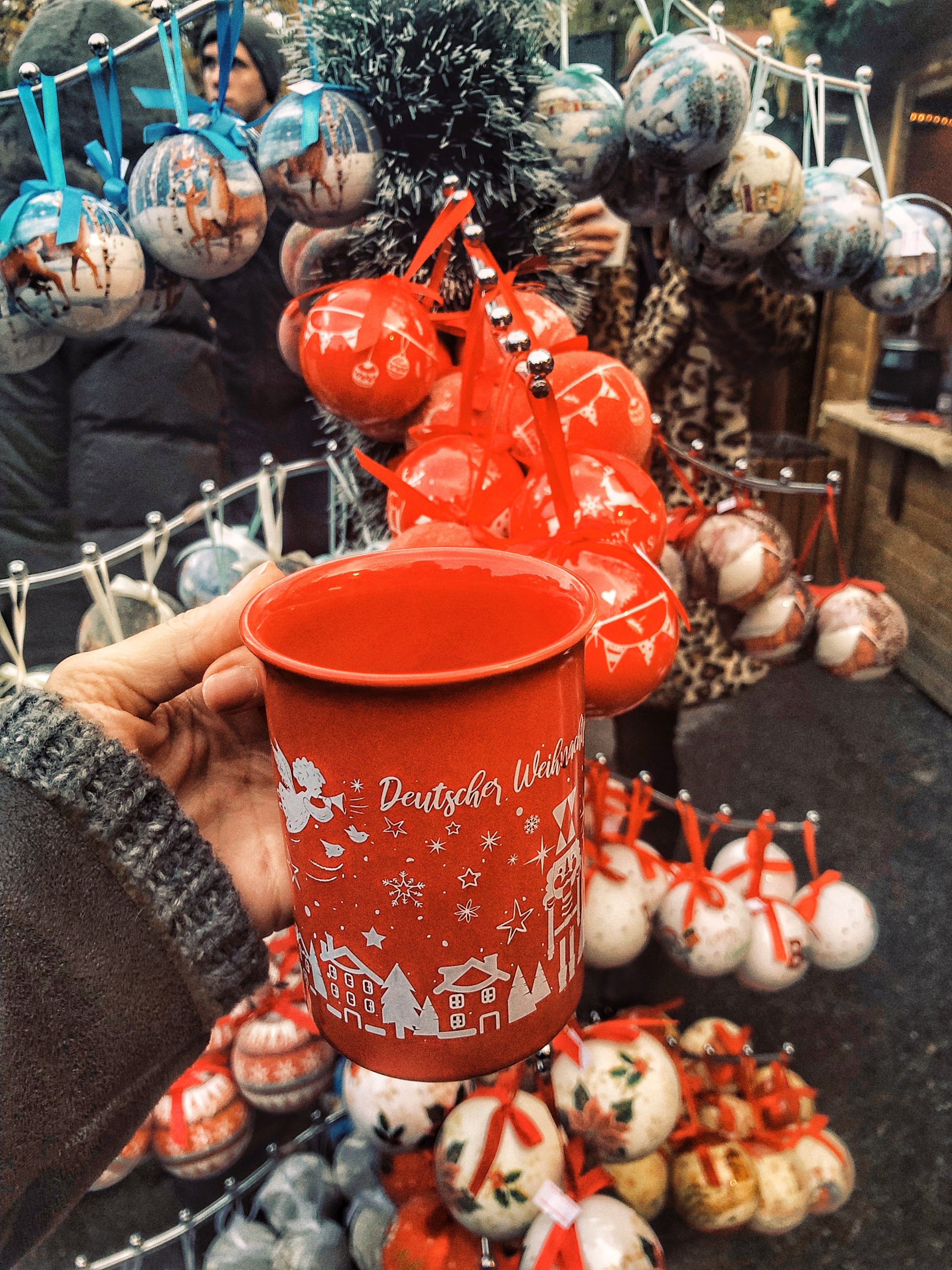 Caption: A photo of a Viennese red mug with Christmas decorations behind it at the Christmas Market, Sofia, Bulgaria.