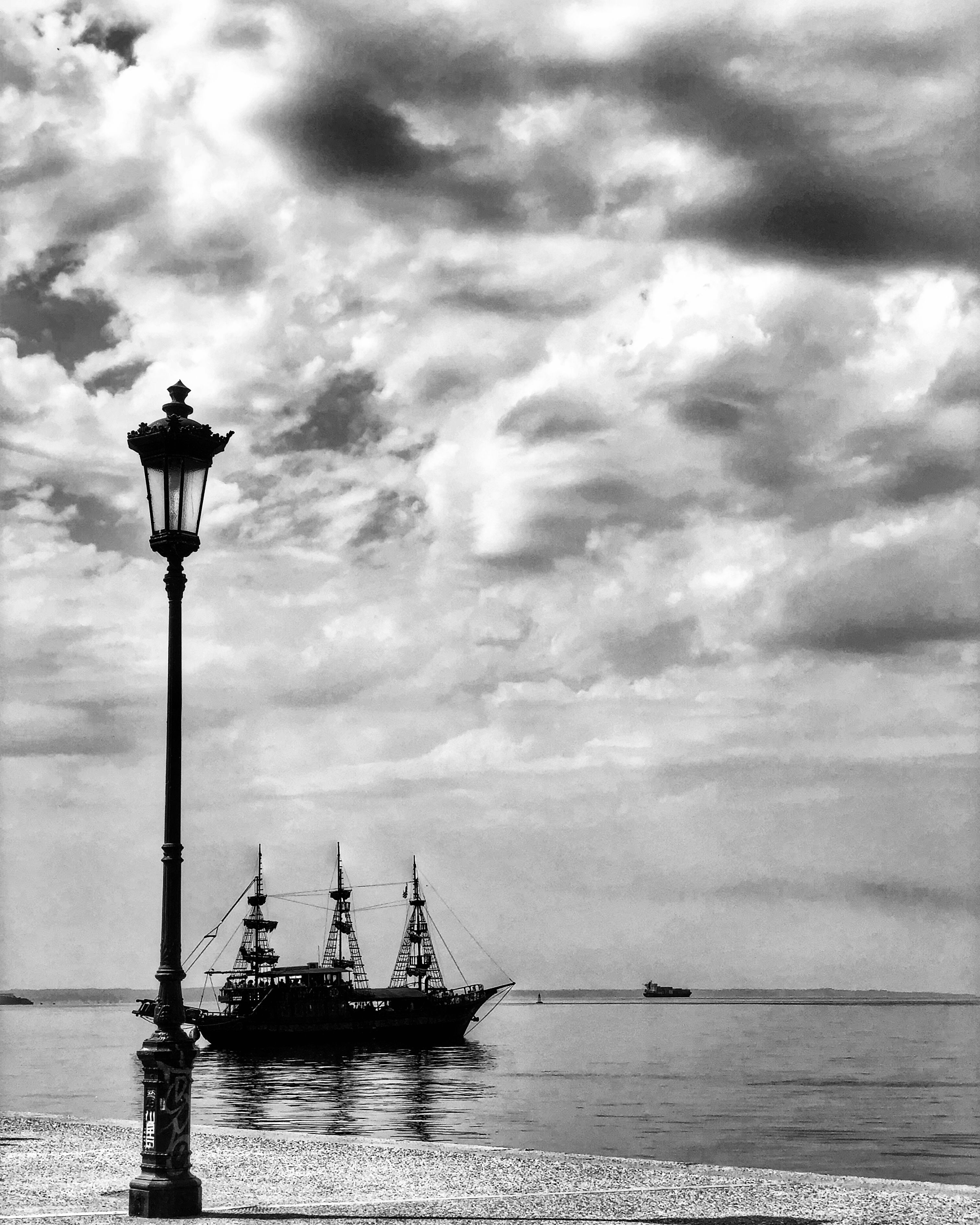 Caption: A black and white photo of an old ship leaving the docks and a lamp in front of it. (Local Guide DanniS)