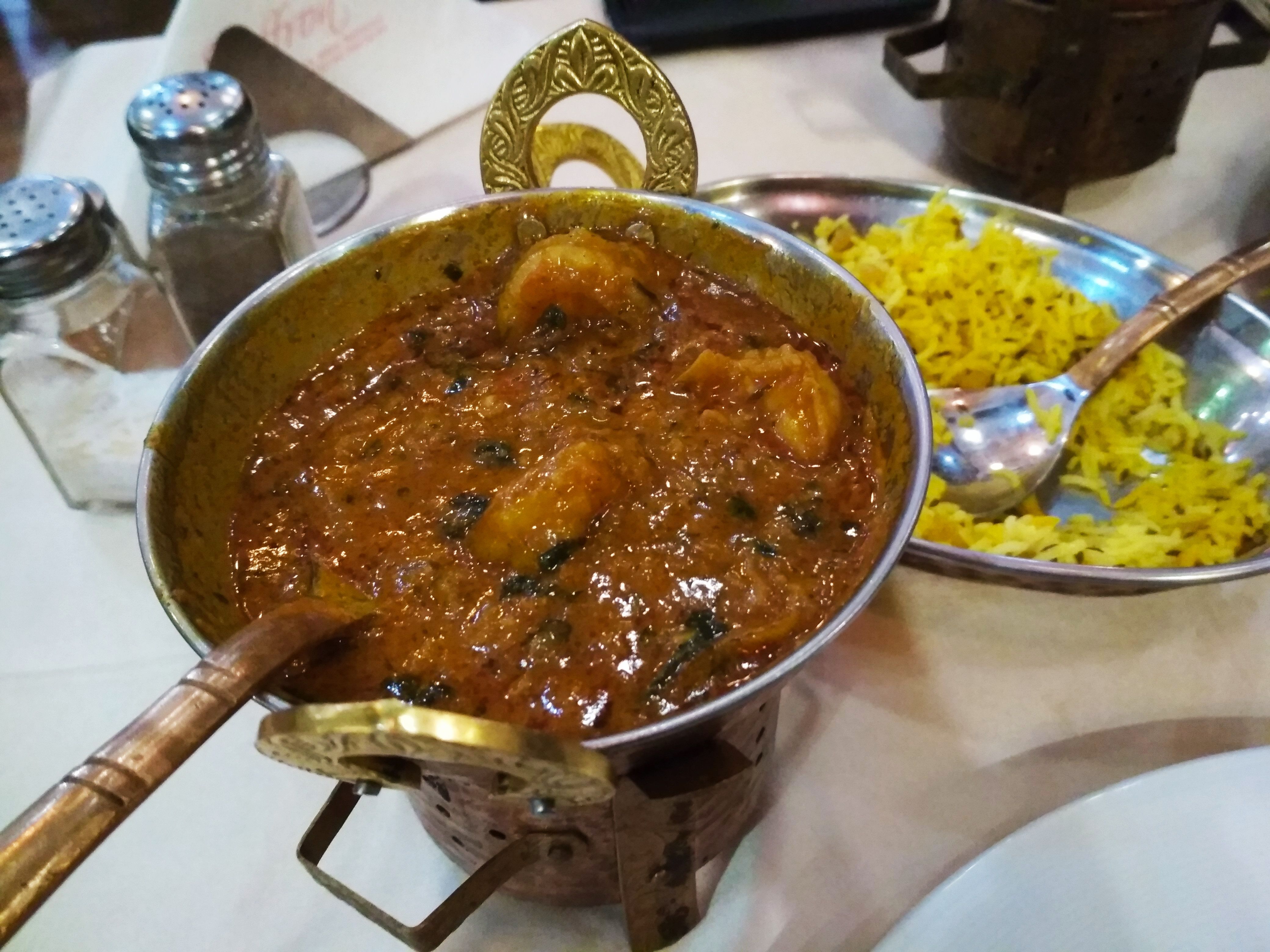 Caption: A photo of a bowl of curry sauce with prawns and a bowl of yellow rice in the background at Saffron Indian restaurant in Sofia, Bulgaria. (Local Guide @DeniGu)