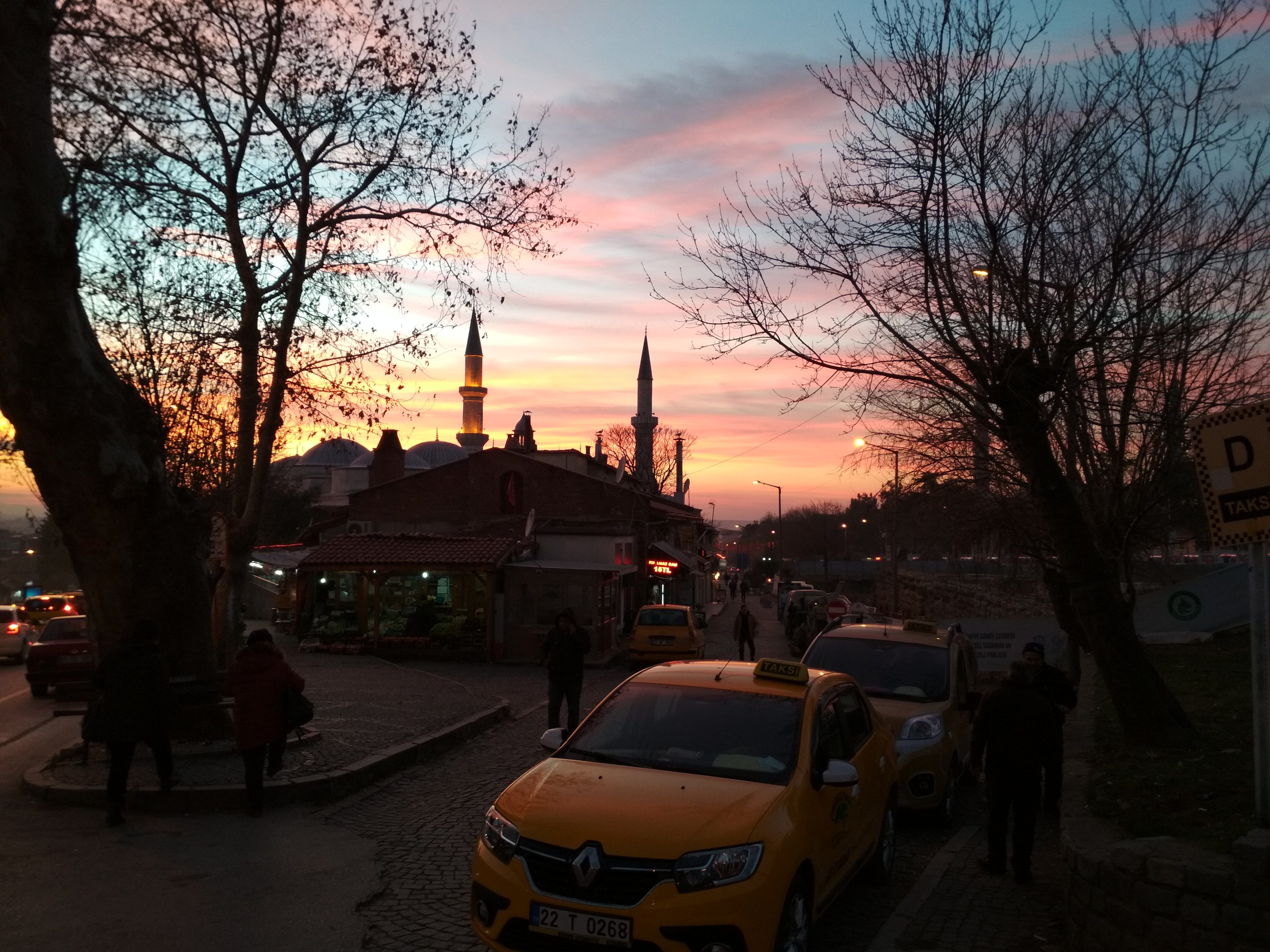 Caption: A photo of the sky in yellow, orange, pink, and purple colours at sunset in Edirne, Turkey. The light is reflected off a bright yellow taxi in the foreground. (Local Guide @DeniGu)