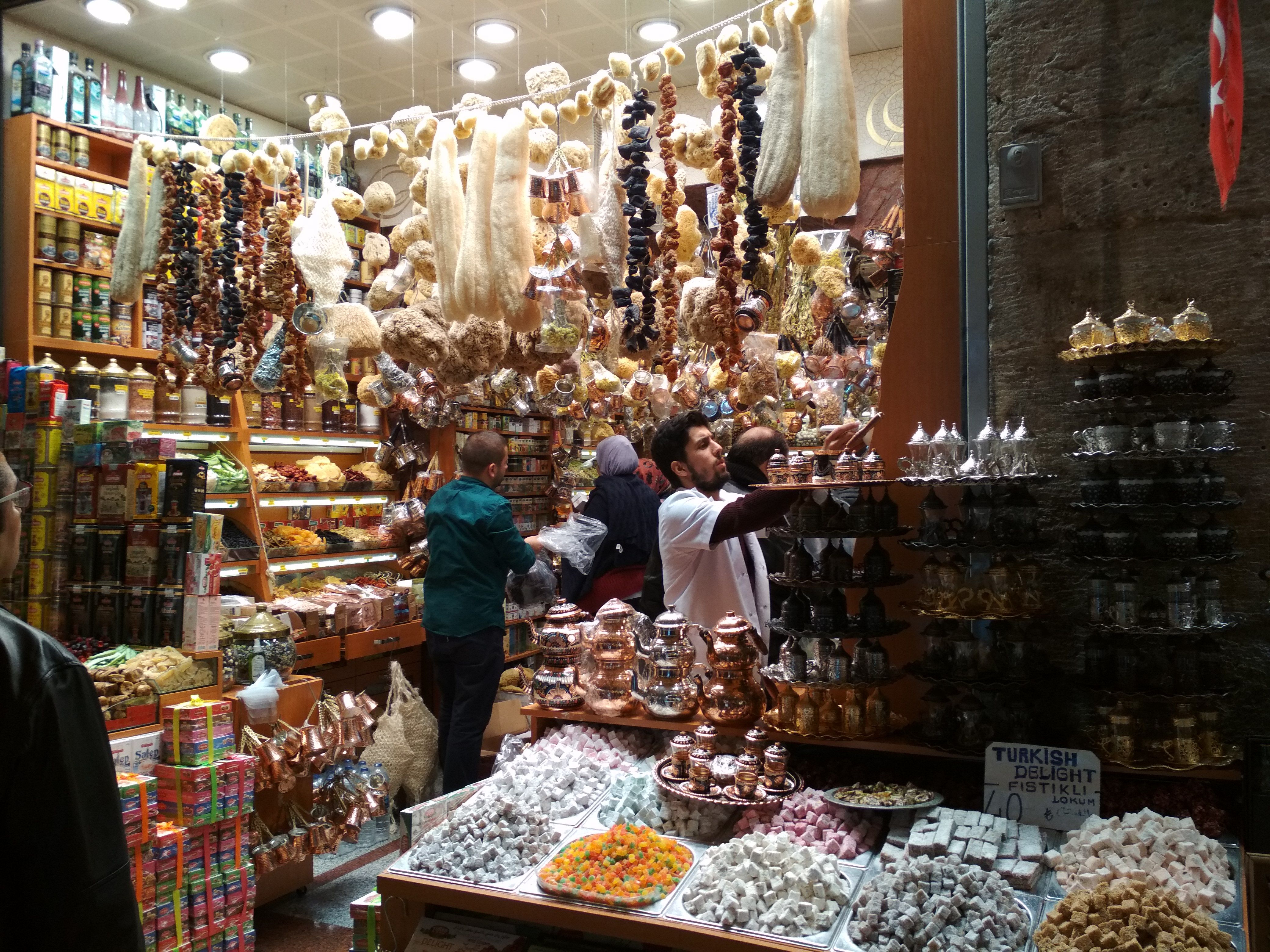Caption: A photo of a shop inside the Egyptian bazaar in Istanbul, Turkey, selling spices, Turkish delight sweets, coffee pots, and various souvenirs. (Local Guide @DeniGu)
