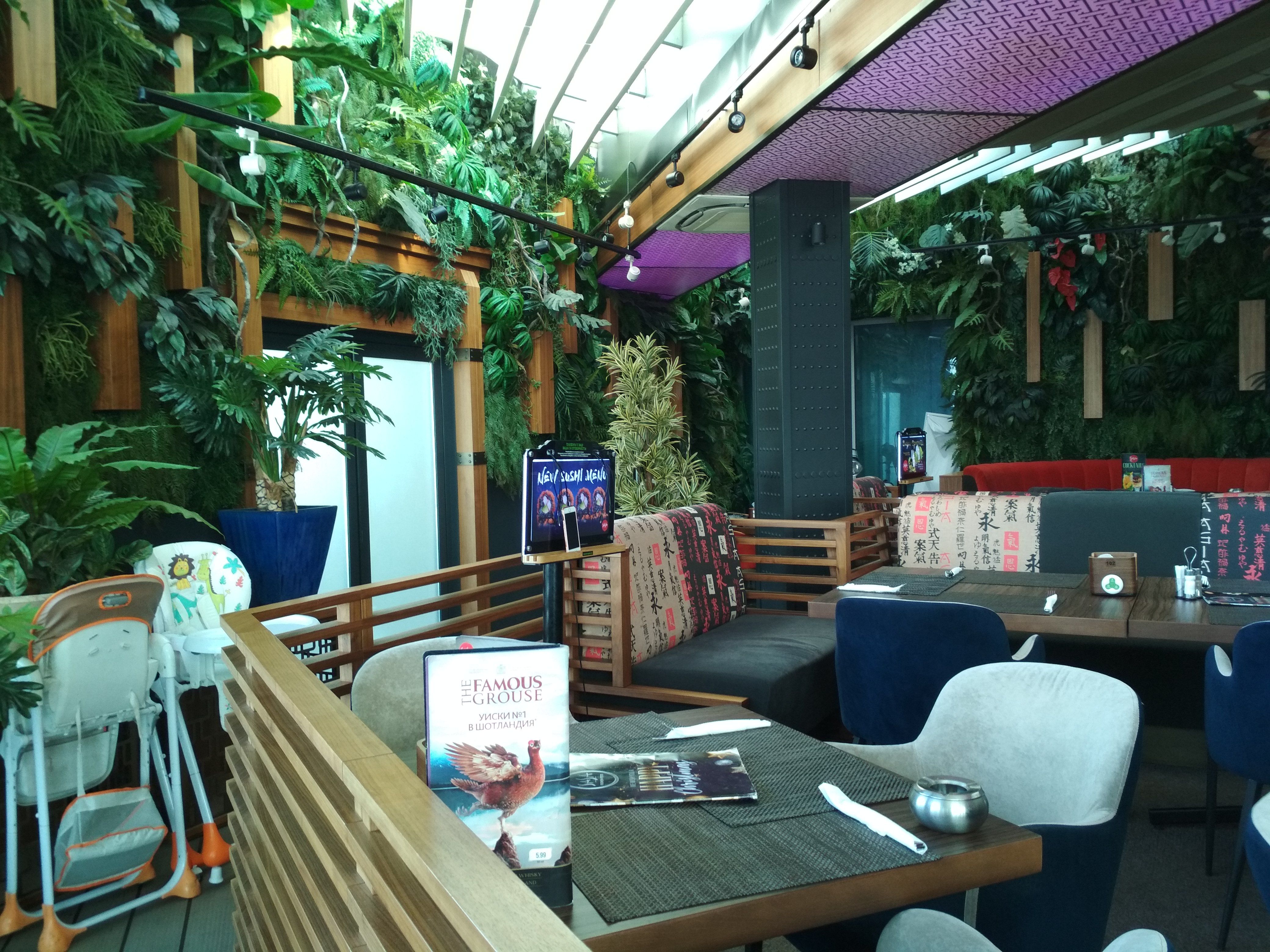 Caption: A photo of enclosed tables and comfortable chairs, with artificial plants covering the walls and high chairs for children in the background taken inside the SASA restaurant in Sofia, Bulgaria. (Local Guide @DeniGu)