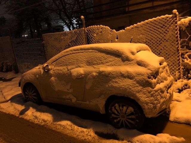 Legenda: meu carro parado na rua próximo a uma casa todo coberto de neve.