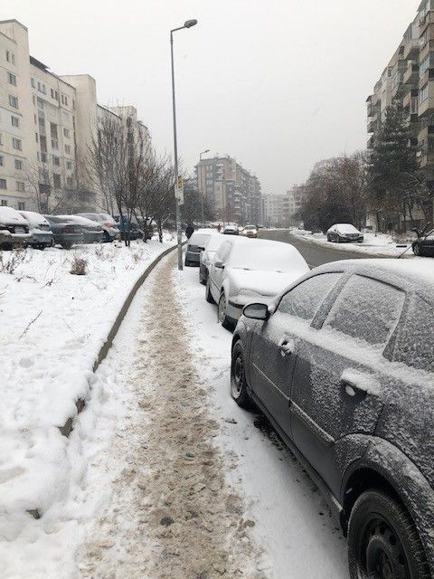 Legenda: Uma foto de uma calçada com coberta com uma neve mais suja e carros cobertos de neve estacionados em cima lado dela. (Local Guide@FelipePK)