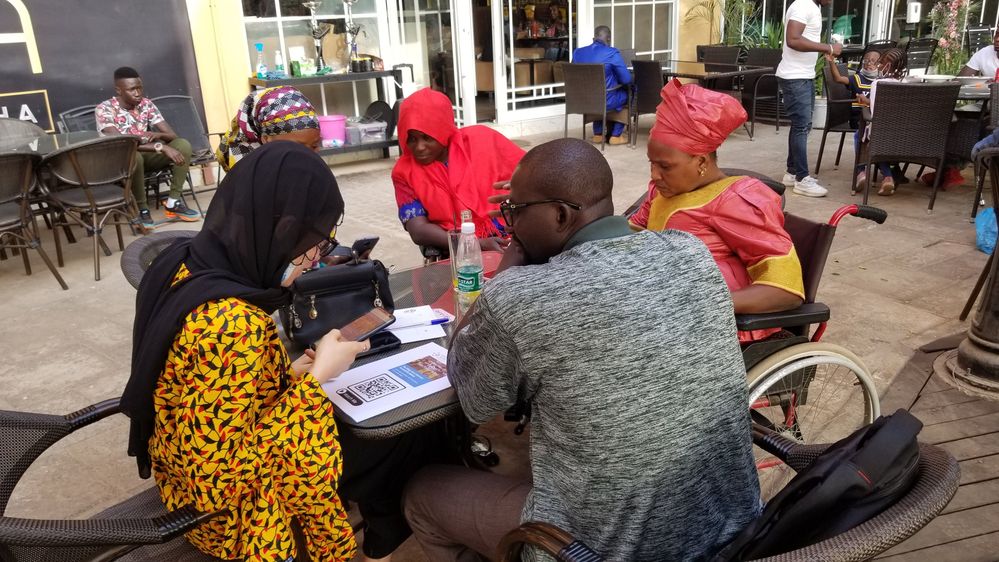 Caption: A group photo of members Gambia Federation of The Disabled - GFD scanning QR Codes to watch Google Maps accessibility videos and taking food photos tips