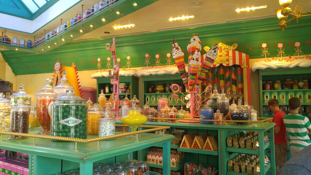 Caption: A photo inside Honeydukes in The Wizarding World of Harry Potter, Universal Studios Orlando, showing green shelves with Harry Potter-inspired candy and treats. (Local Guide Lexa C)