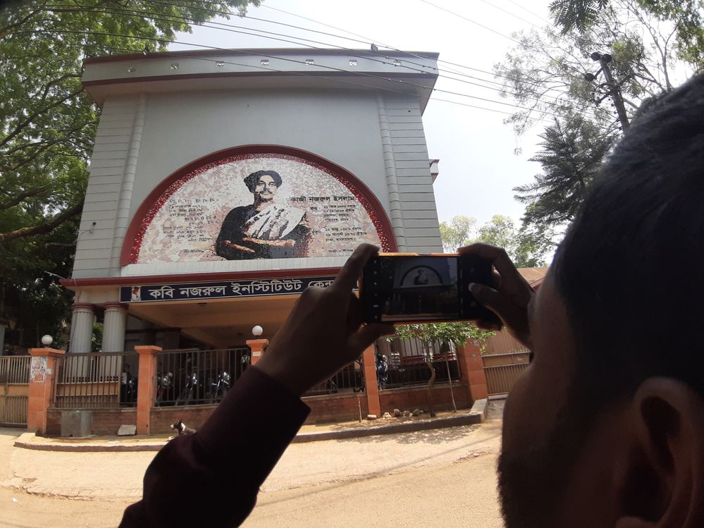 Caption: A front view of Nazrul institute Center  focusing by a meet up participant to take photograph with his mobile