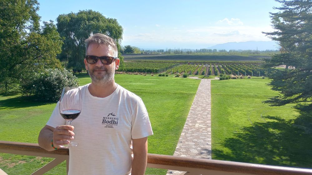 Caption: Local Guide SebaasC making a toast, behind the vineyards and hill of Mendoza.
