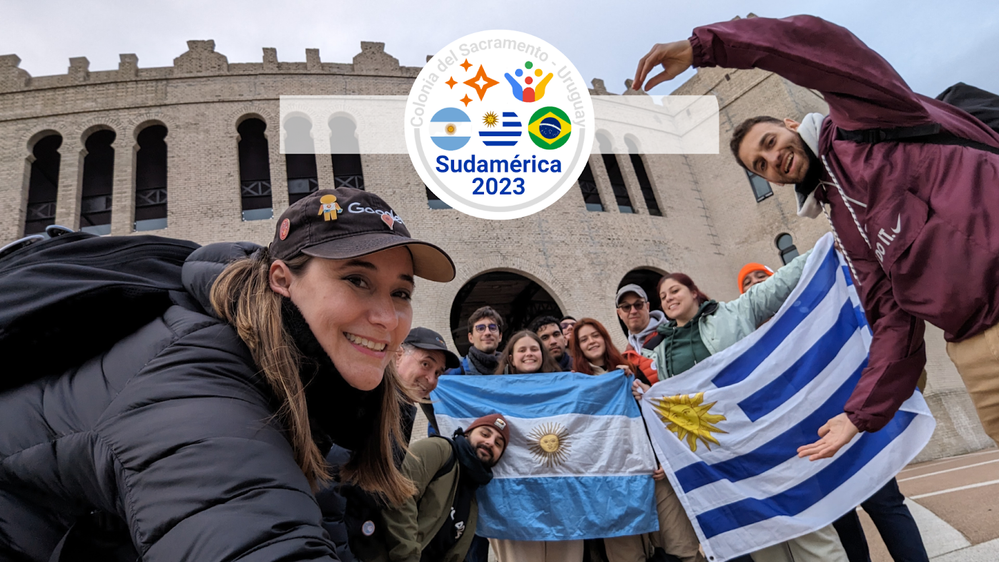 Foto grupal frente a la Plaza de Toros de Colonia con las banderas de Argentina y Uruguay y con el Logo que dice "Sudamérica 2023 - Colonia del Sacramento - Uruguay" al frente.
