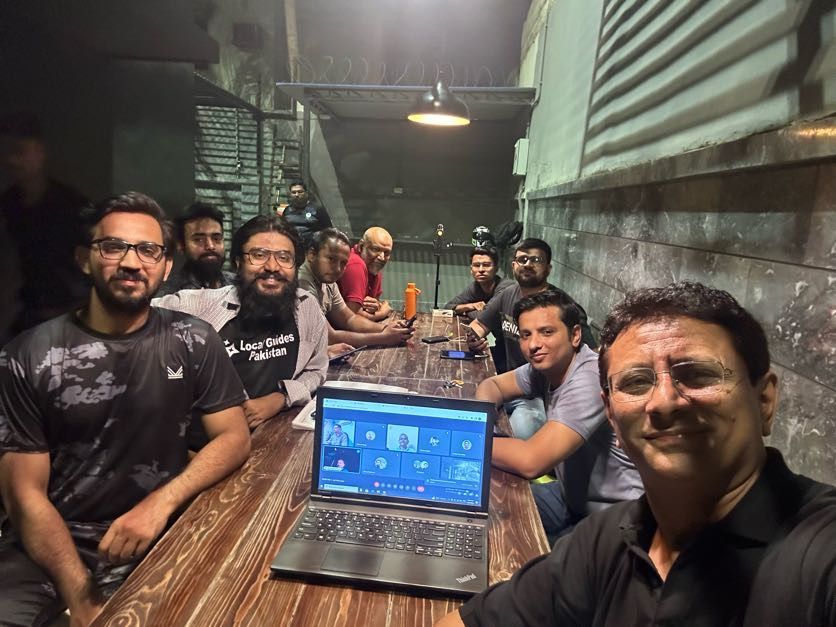 Caption: A selfie of Kashif and other Pakistani Local Guides during a meet-up, with a laptop on the table showing more participants tuning in virtually. (Courtesy of Local Guide @KashifMisidia)
