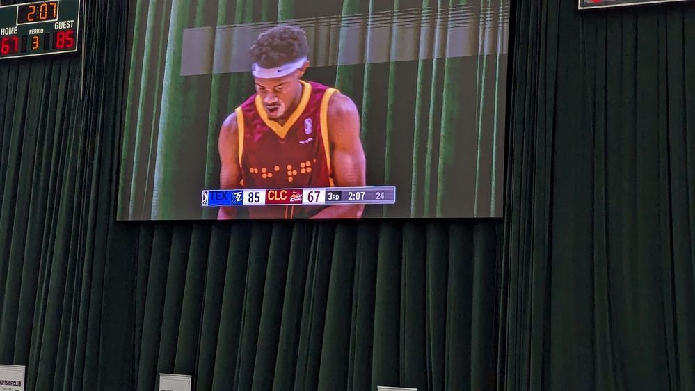 Caption: A photo featuring the a Charge player and the front of his braille embossed jersey on the large LED screen