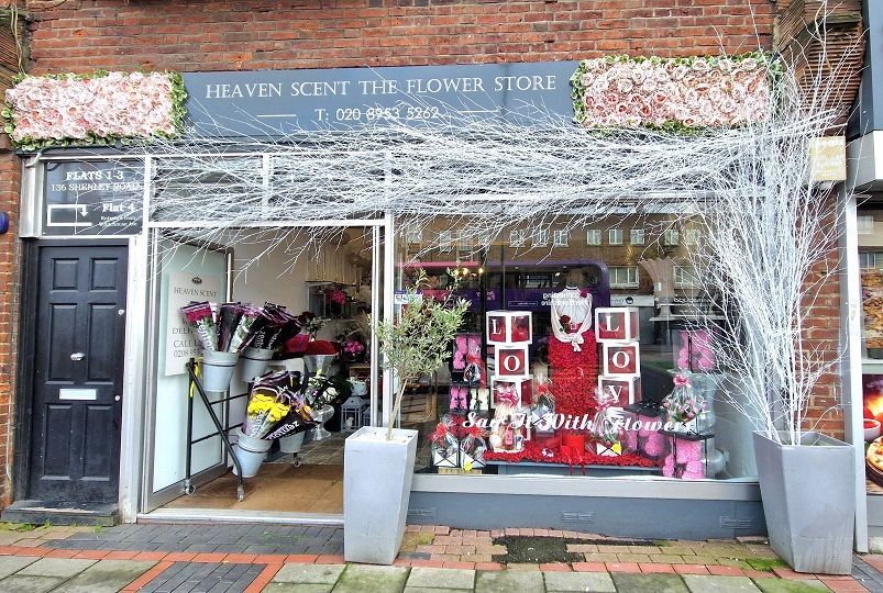 Caption: A storefront photo of Heaven Scent The Flower Store showing a red, white, and pink decoration of flowers, balloons, and glass cubes that spell the word “love.” (Courtesy of Local Guide @abermans)
