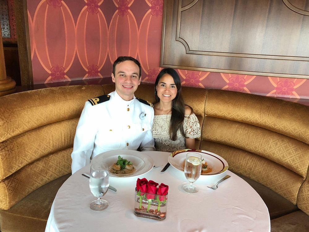 Caption: A photo of Local Guide Priscila and her partner sitting at a table decorated with three red roses and enjoying a meal for Valentine’s Day on board the Disney Dream cruise ship. (Courtesy of Local Guide @PriscilaJimenez)