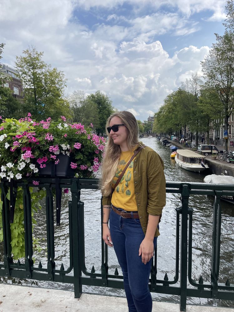Caption: A photo of Local Guide Sarah standing on a bridge over one of Amsterdam’s canals. (Courtesy of Local Guide @Calicodreamin)