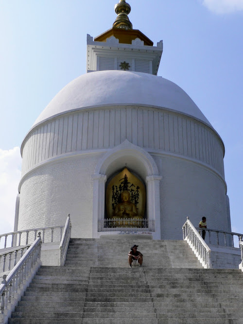 Caption: @AdamGT  sitting on the steps of the brilliant-white and large World Peace Pagoda, in Pokhara, Nepal