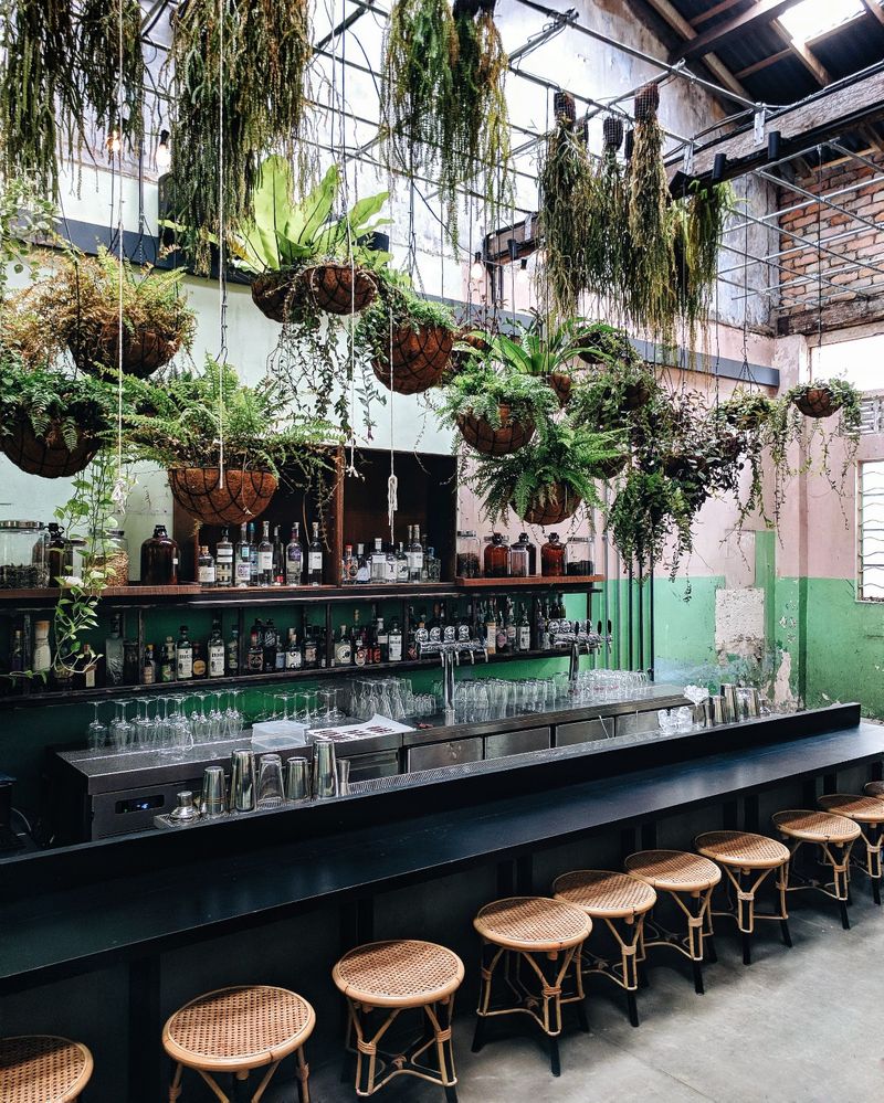 Caption: The interior of Botakliquor, an airy bar with hanging plants in in Kuala Lumpur, Malaysia.