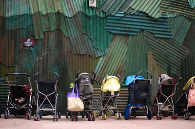 A row of strollers lined up against a wall with a sign noting the space is for stroller parking (Getty Images)