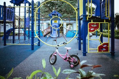 A playground featuring a colorful jungle gym framing a child's pink bicycle with training wheels (Getty Images)