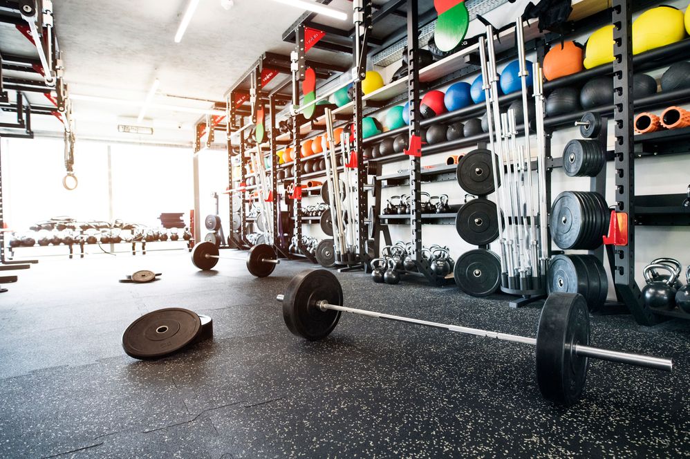Caption: A photo of a training room in a gym with stacks of weights, barbells, kettlebells, and exercise balls. (Getty Images)