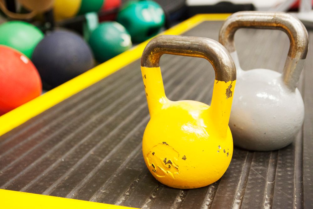 Caption: A close-up photo of two kettlebells and other gym equipment in the background. (Getty Images)