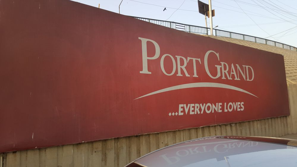 A sign board of Port Grand under the bridge